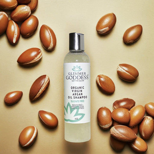 Glimmer Goddess shampoo bottle surrounded by argan oil seeds on a beige background